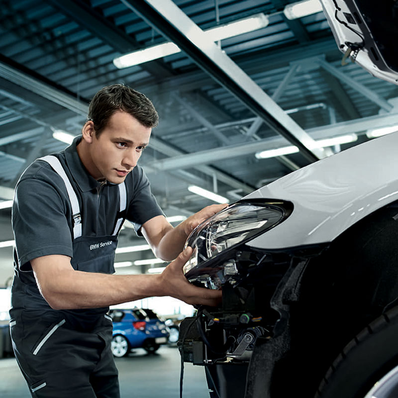 A BMW service technician replacing the headlights of a BMW vehicle in the service center.