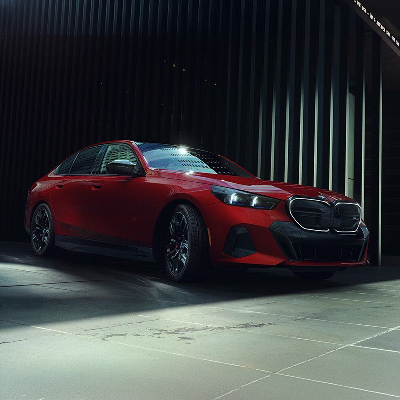 A red BMW i5 parked in front of a building.