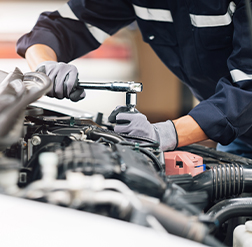 Close-up of a service technician performing maintenance on a vehicle's engine.