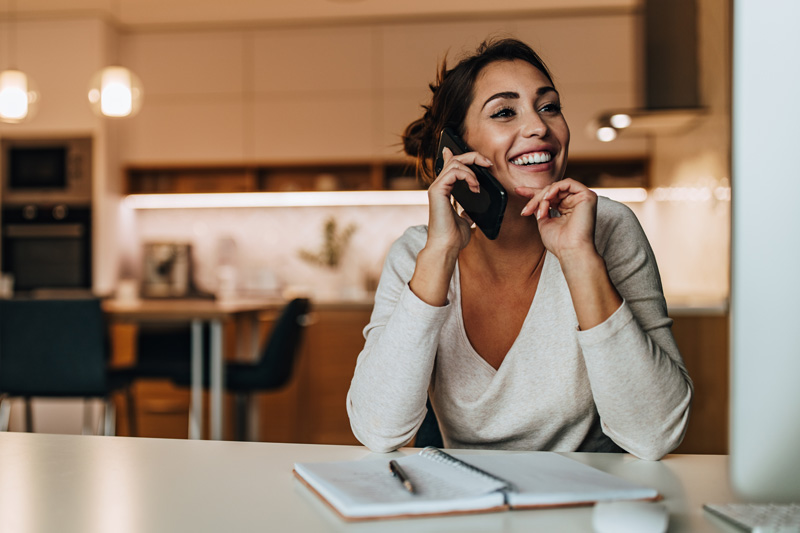 A woman on their cell phone smiling.