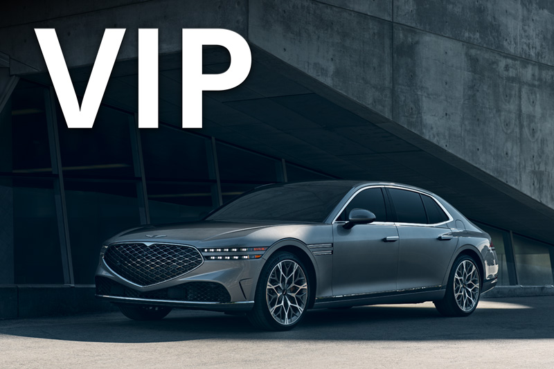 A silver Genesis G90 parked in front of a building.