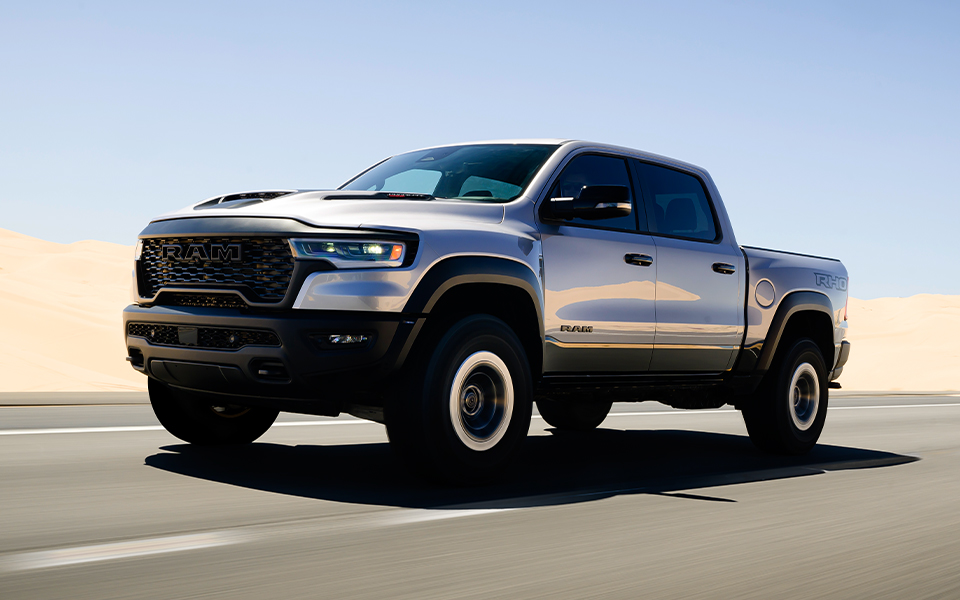 A silver Ram 1500 truck driving on a highway by a desert
