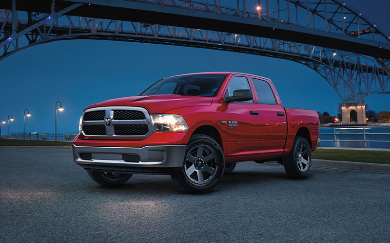 A Ram 1500 parked by a river at night with the headlights on