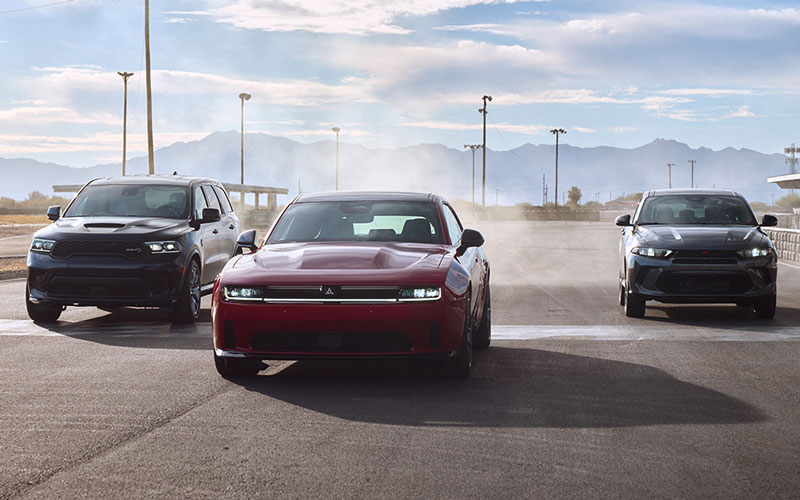 Three Dodge vehicles racing down a street.