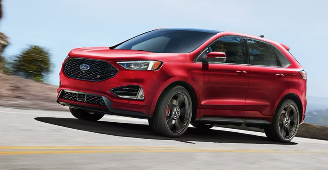 The 2024 Ford Edge driving away from a city in the distance.