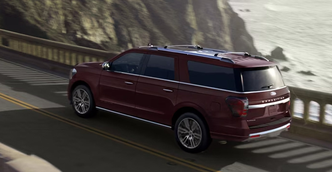 A 2024 Ford Expedition driving on a highway on a cliff by the ocean.