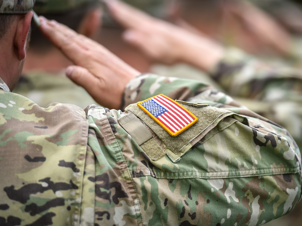 Close-up of a soldier in uniform saluting from behind.