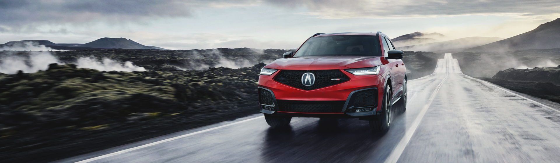 A red Acura MDX Type S mid-size luxury SUV driving on a wet road.