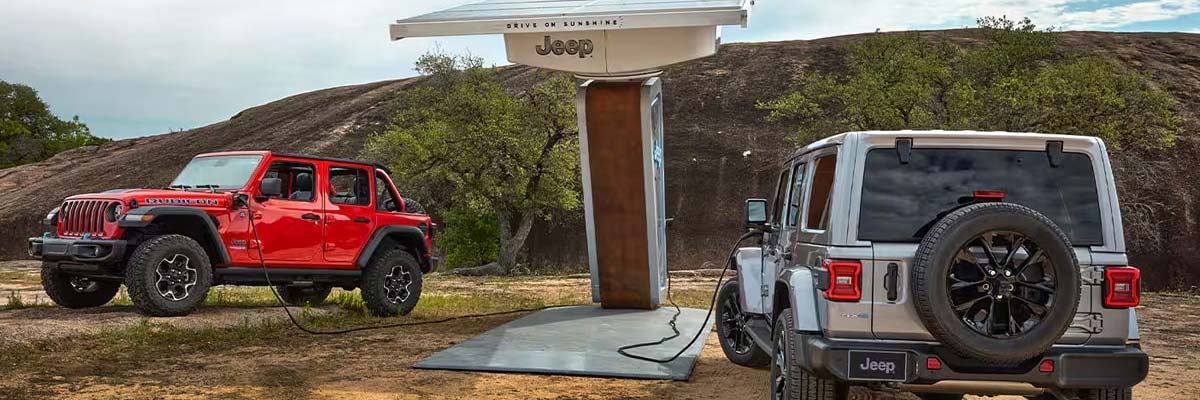 2 Jeep 4xe parked at a Jeep charging station and plugged in.