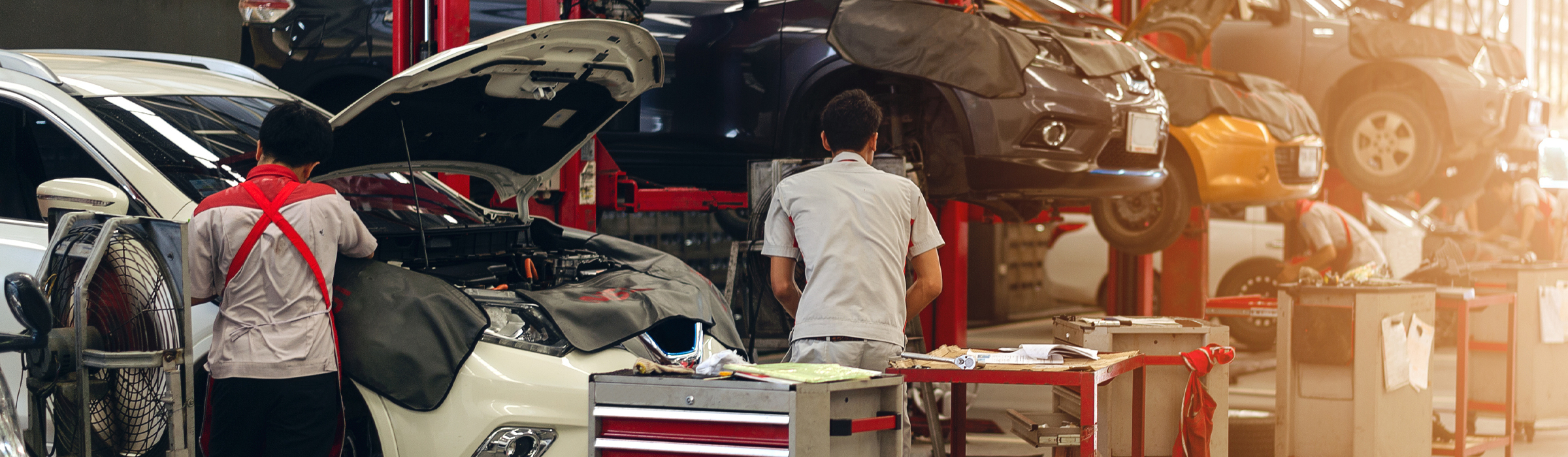 Service technicians performing vehicle maintenance on vehicles in the service center