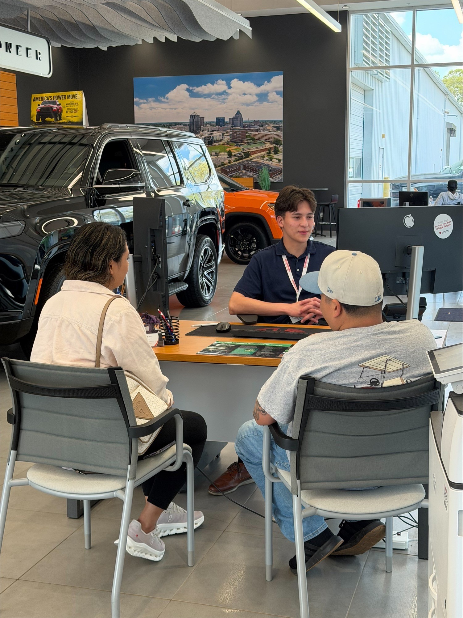 Spanish speaking employee at his desk with clients.