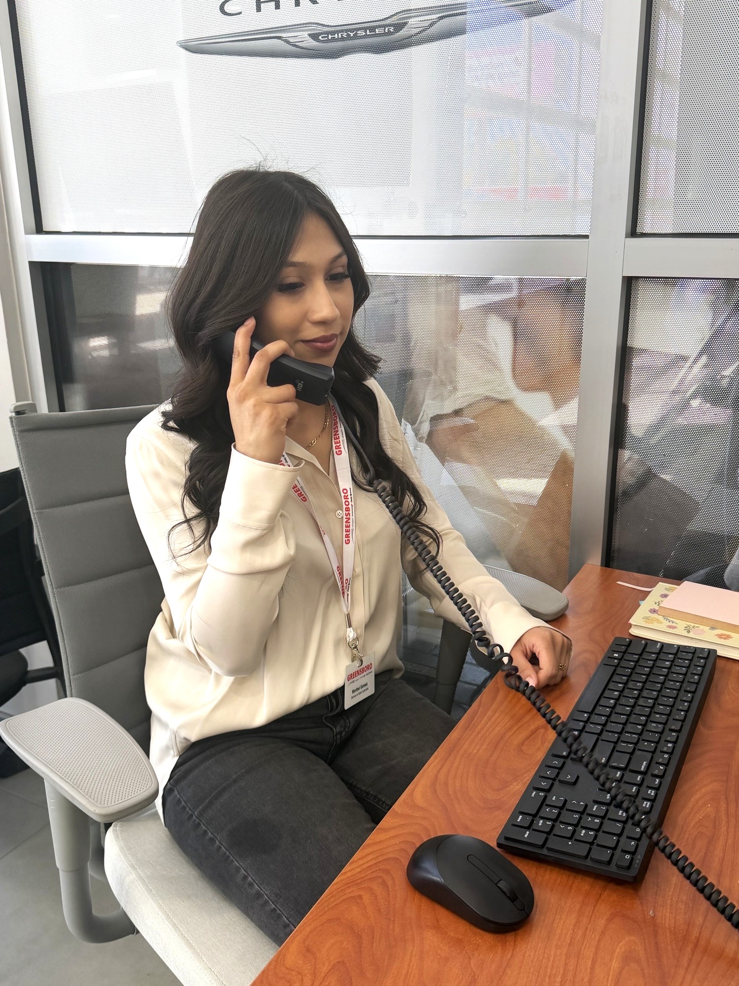 Spanish speaking employee at her desk on the phone in the dealership.