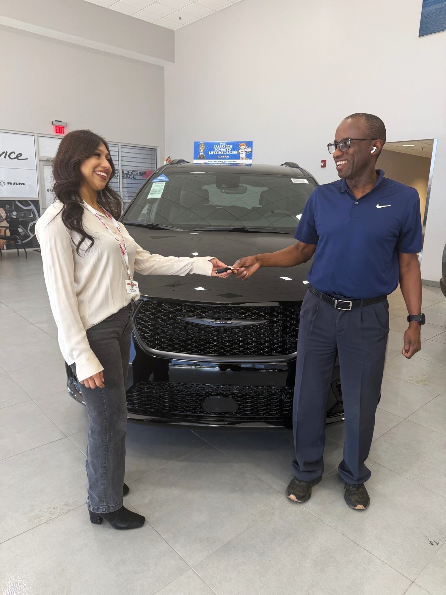 Spanish speaking employee handing off keys to a customer.