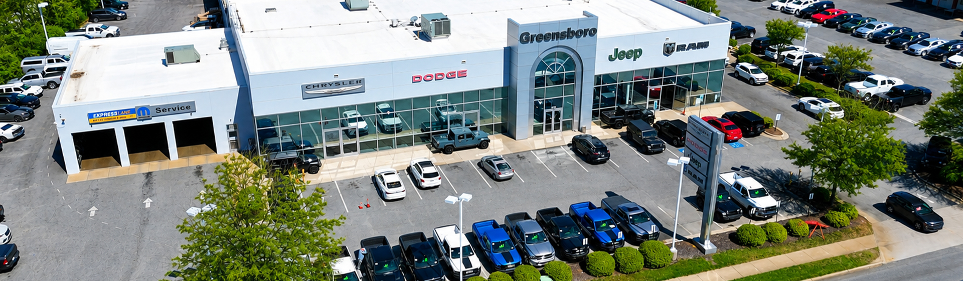The storefront of the Greensboro Chrysler Dodge Jeep Ram dealership and vehicle lot.