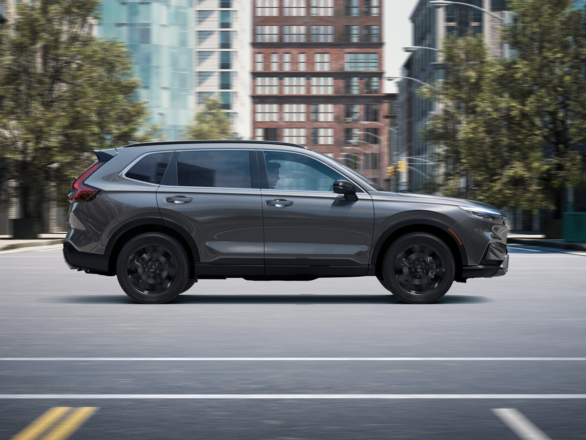 A silver Honda CR-V crossover SUV driving through city streets.