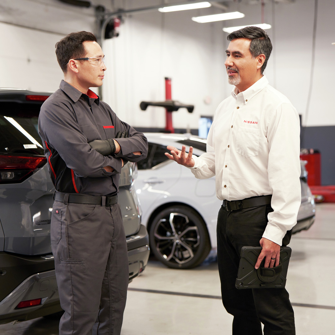 Nissan service technicians chatting in a Nissan service center.