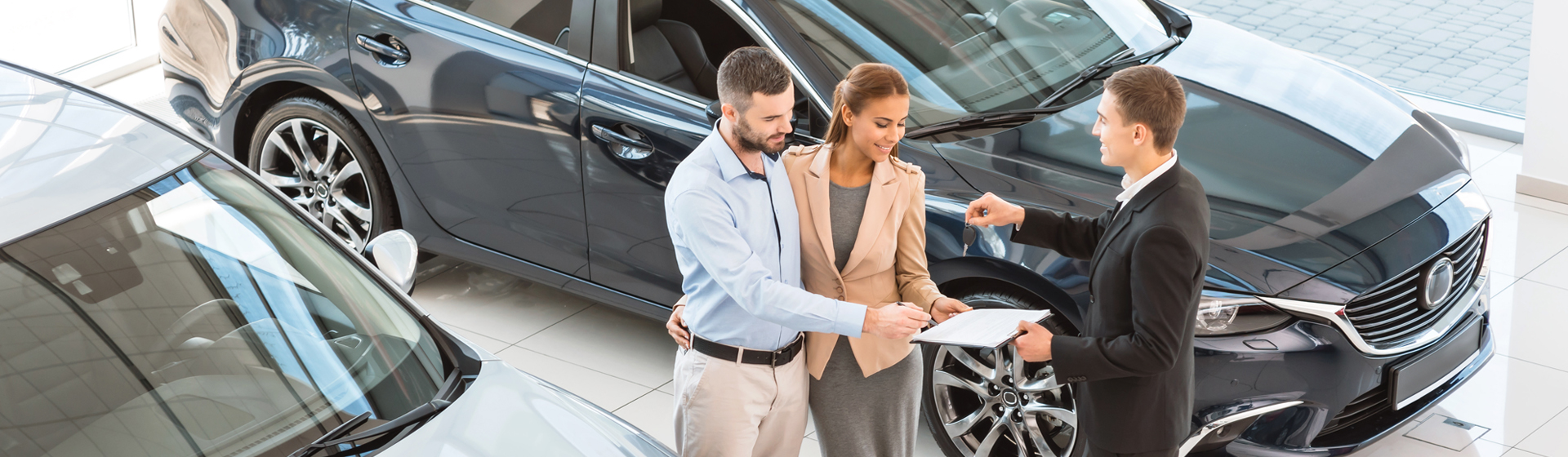 A couple in the dealership looking at paperwork the salesperson is showing them.