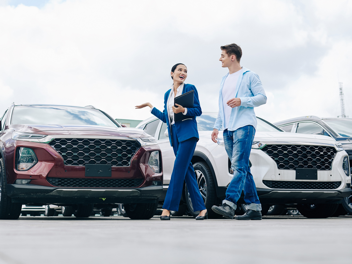 A car salesperson showing a new buyer the vehicles in the dealership's lot.