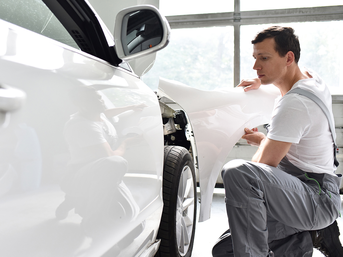 A service technician replacing a panel on a car