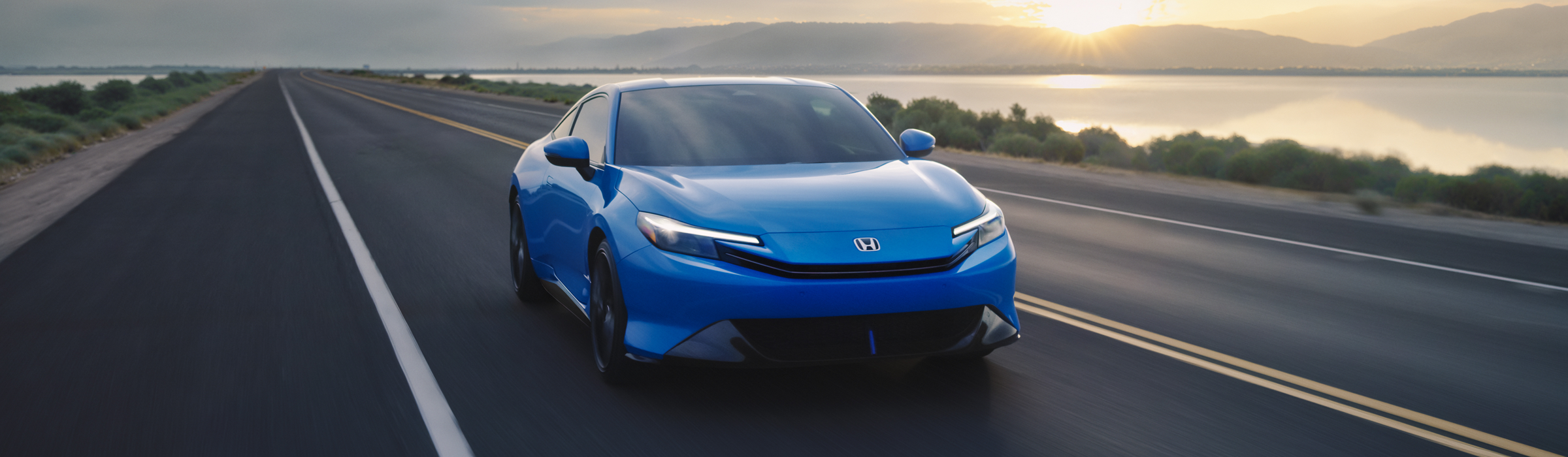 The front view of a blue Honda Prelude driving on the highway.