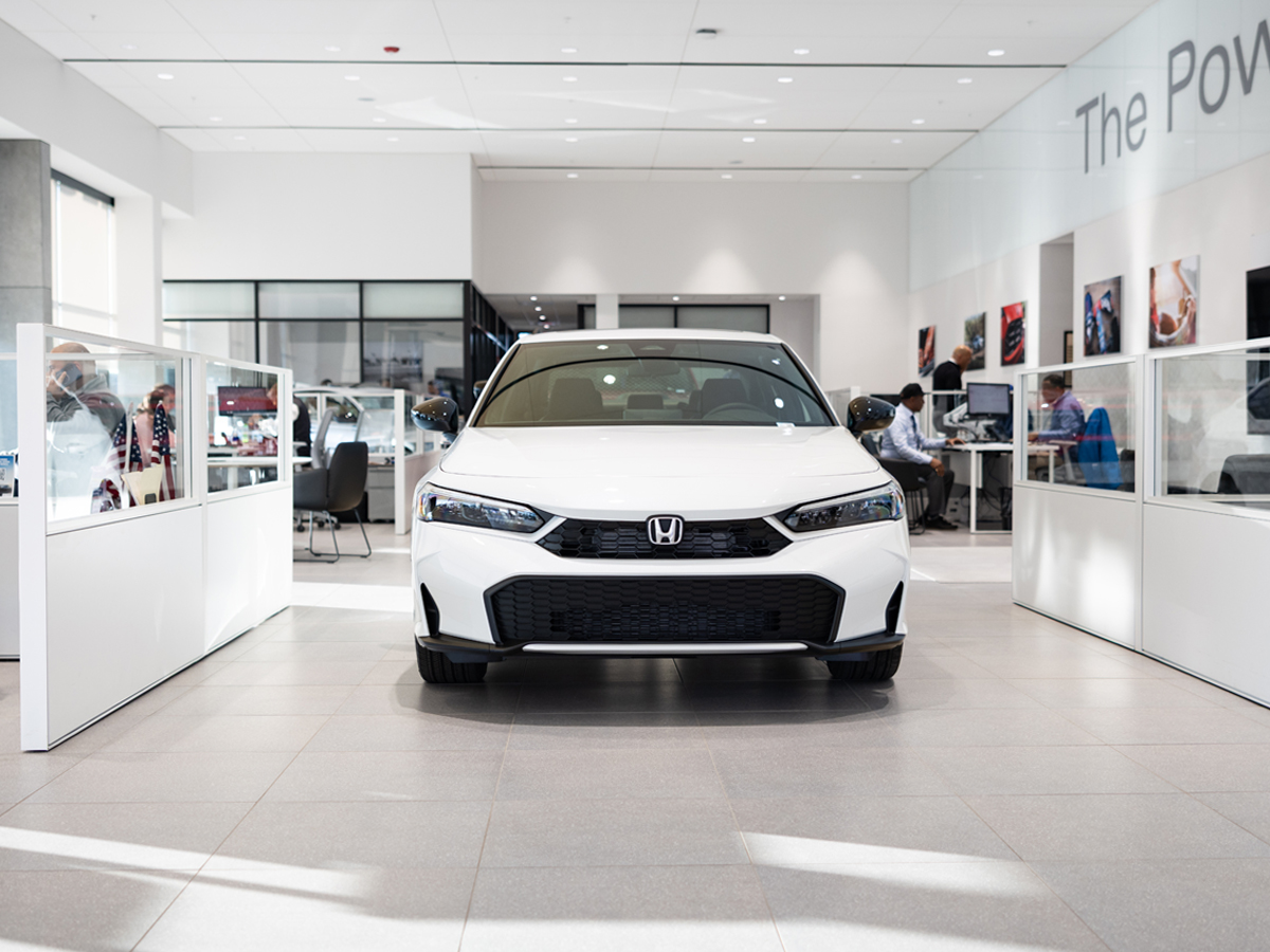 A white Honda Civic Sport sedan parked inside the dealership.