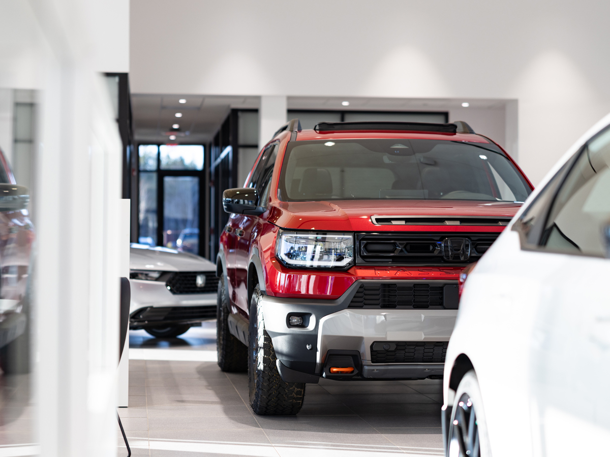 Multiple Honda vehicles parked inside the dealership including a red Honda Passport