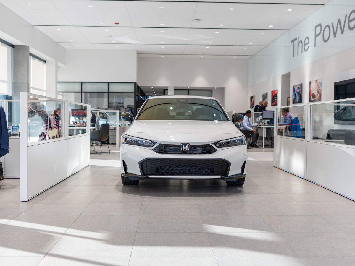 A white Honda Civic sedan parked inside the dealership on display in the showroom.