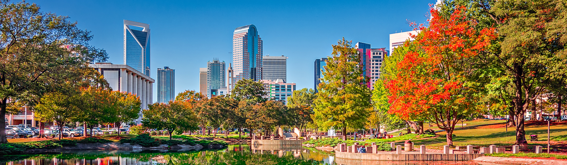 The skyline of Charlotte, North Carolina, viewed from Marshall Park with its scenic pond and autumn trees.
