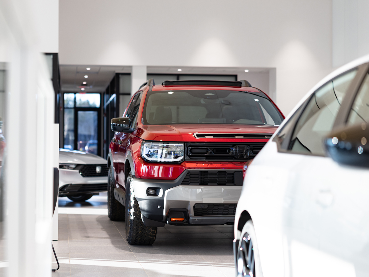 A red Honda Passport parked inside the dealership on display in the showroom.
