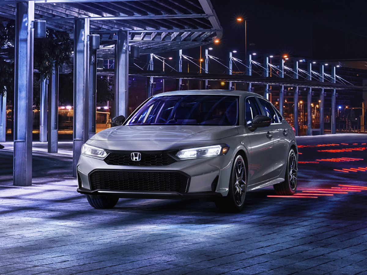 A gray Honda Civic parked on a paved urban street at night..