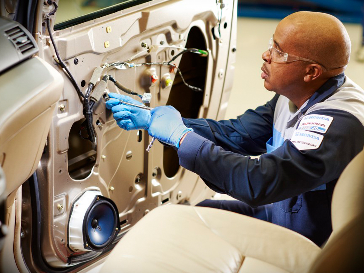 A Honda Service Technician working on a vehicle door interior.