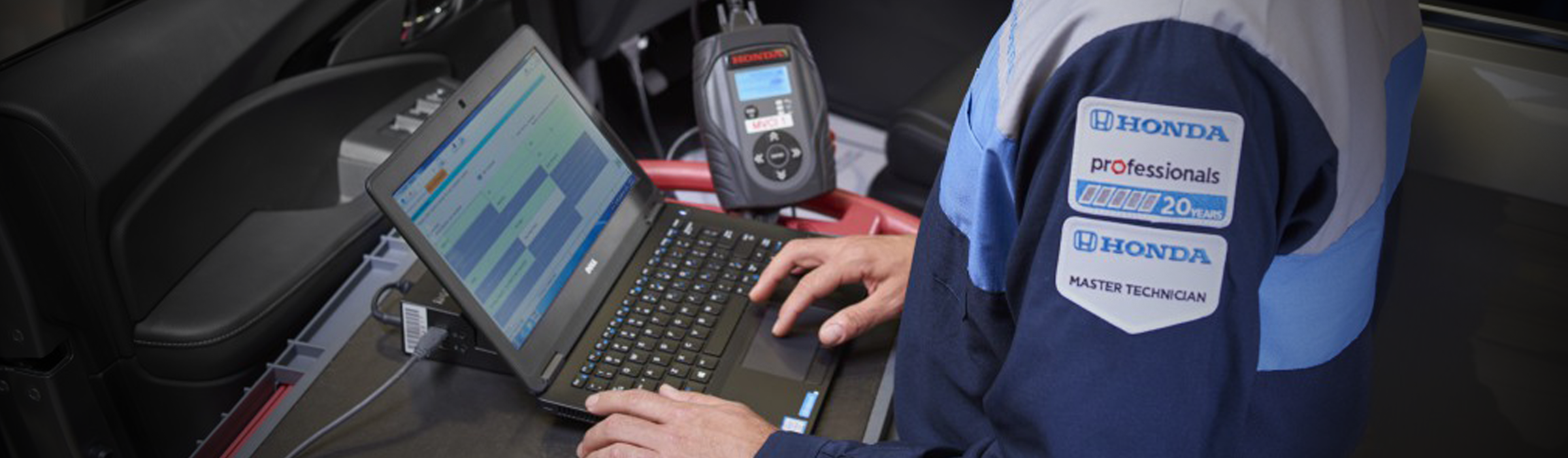 A Honda Service Master Technician working on their laptop in the service center