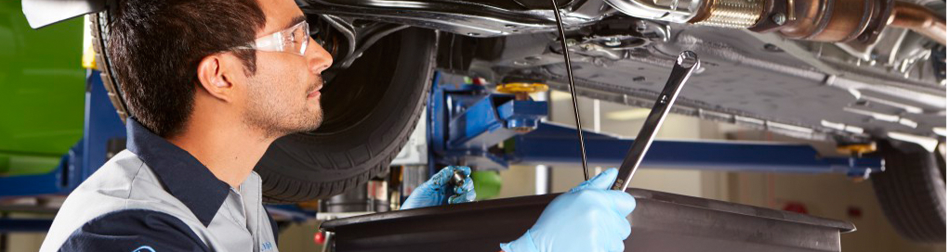A service technician under a vehicle on a lift in the service center.