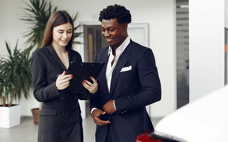 A car salesperson in the dealership with a customer.