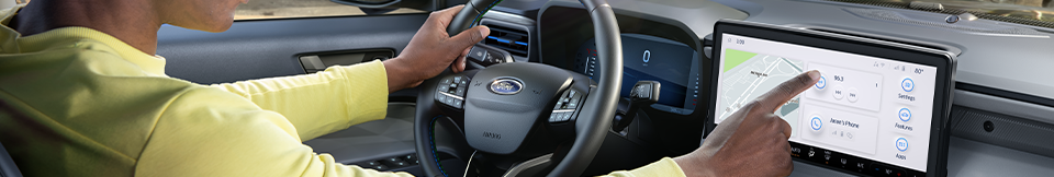 A driver tapping on the display of a Ford Maverick infotainment center screen.