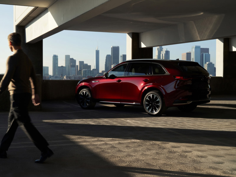 A Mazda CX-90 parked in a parking garage with a view of the city