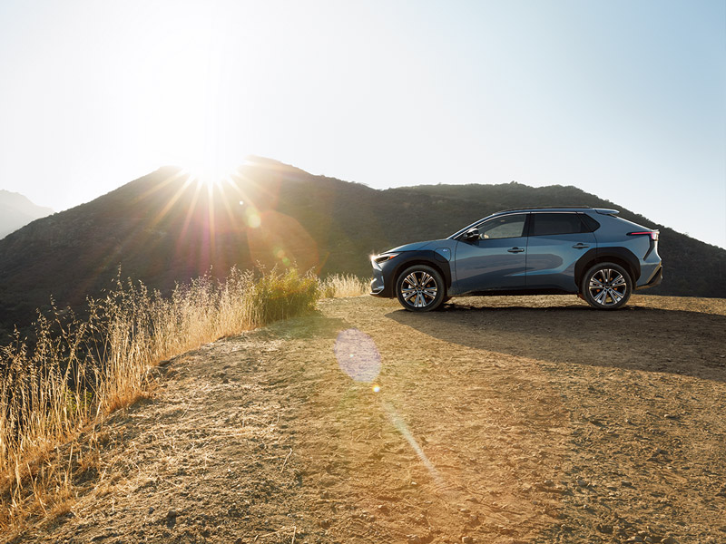 A Subaru Solterra parked off-road on a dirt patch in the mountains