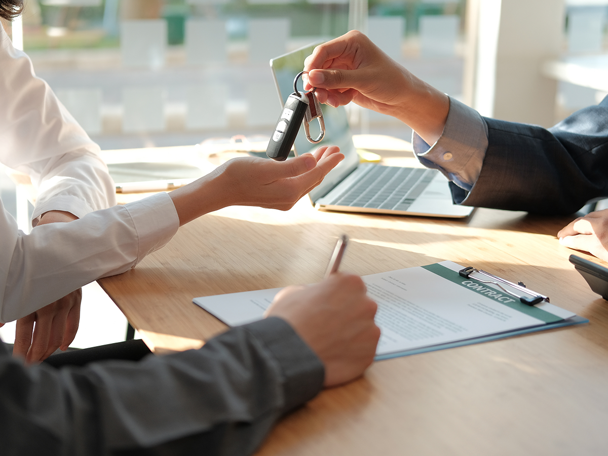 A car salesperson handing a new car owner their car keys