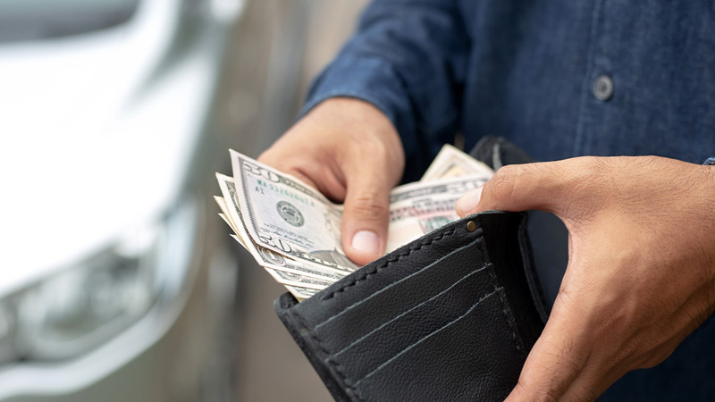 A close-up on someone's hands putting money in their wallet