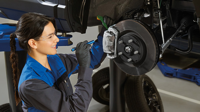 A Subaru service technician performing service on a vehicle's brakes in the service center