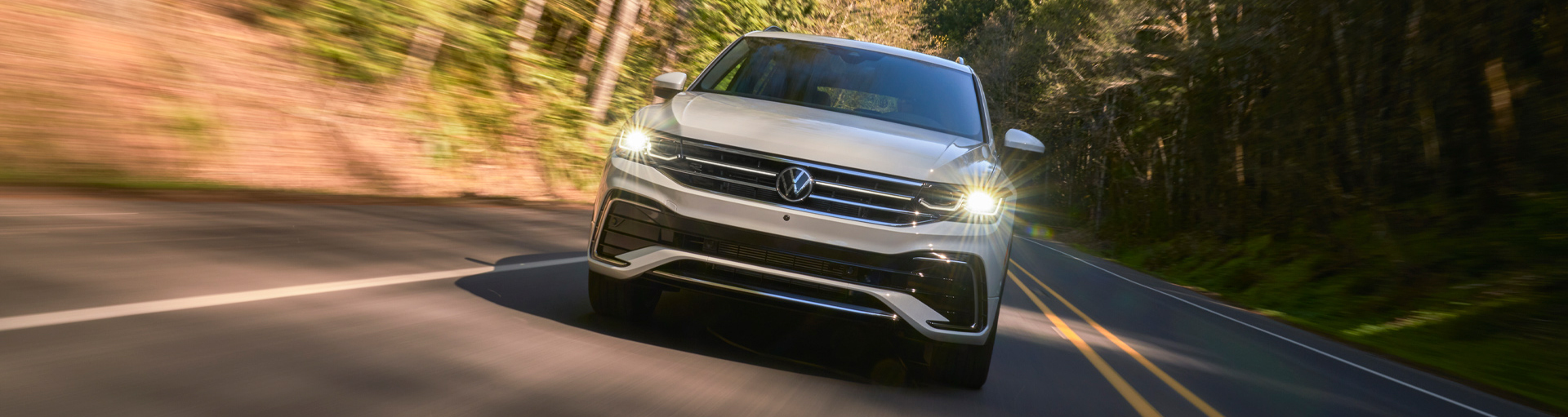 The front of a Volkswagen Tiguan as it drives towards the camera with its headlights on
