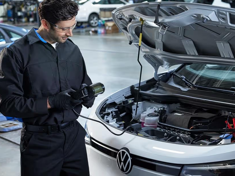 A Volkswagen service technician performing maintenance on a Volkswagen vehicle in the service center