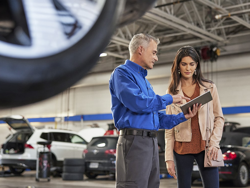 A Volkswagen service technician discussing vehicle maintenance with a car owner