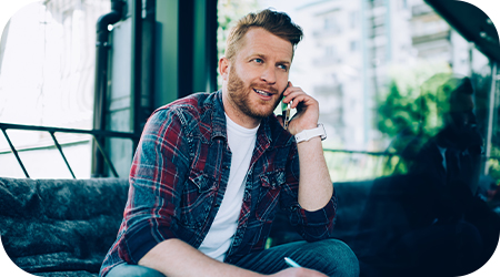 A man sitting on his couch at home while on the phone
