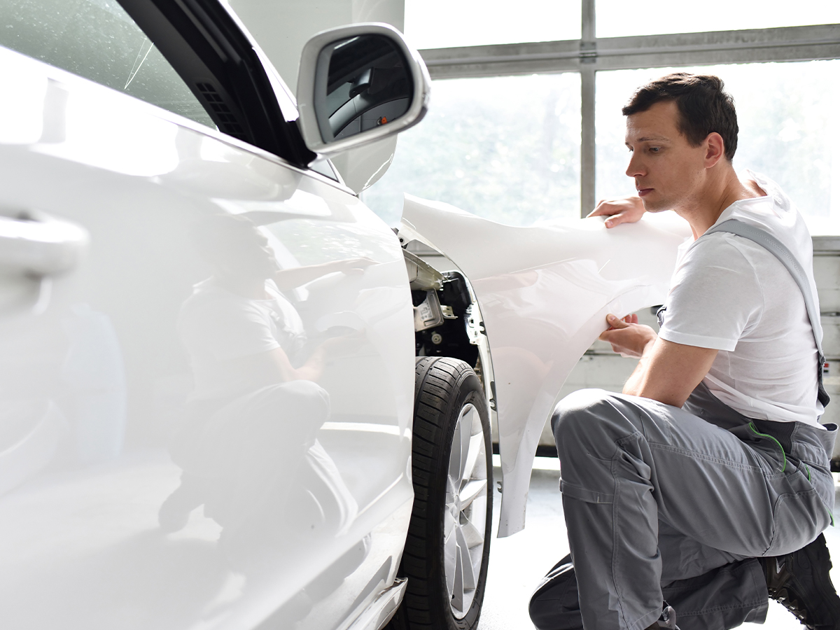 A service technician replacing a panel on a car