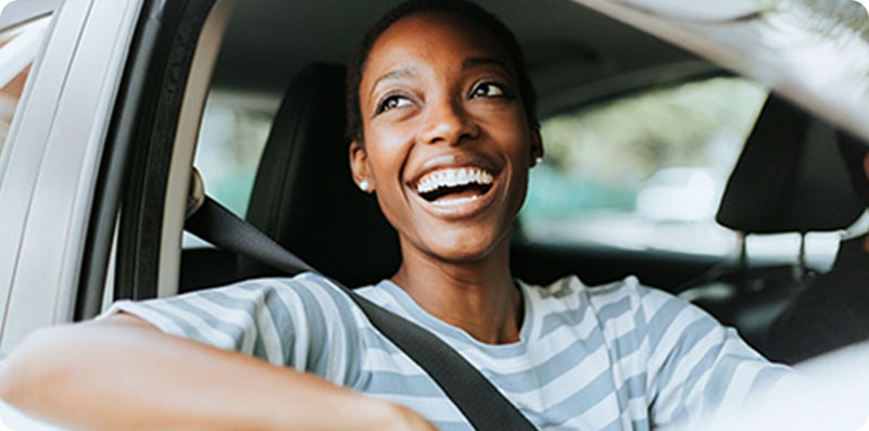 Woman smiling while behind the wheel of her vehicle.