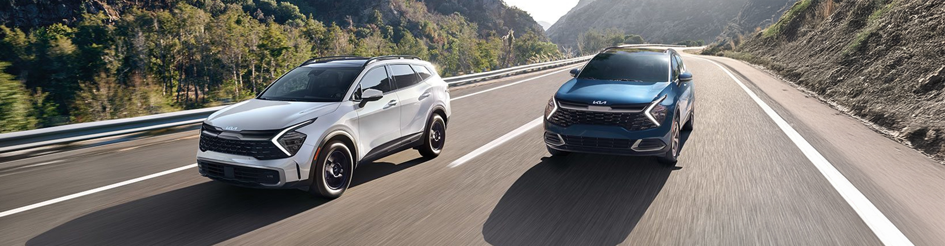 Two Kia Sportage vehicles in different colors driving down the highway
