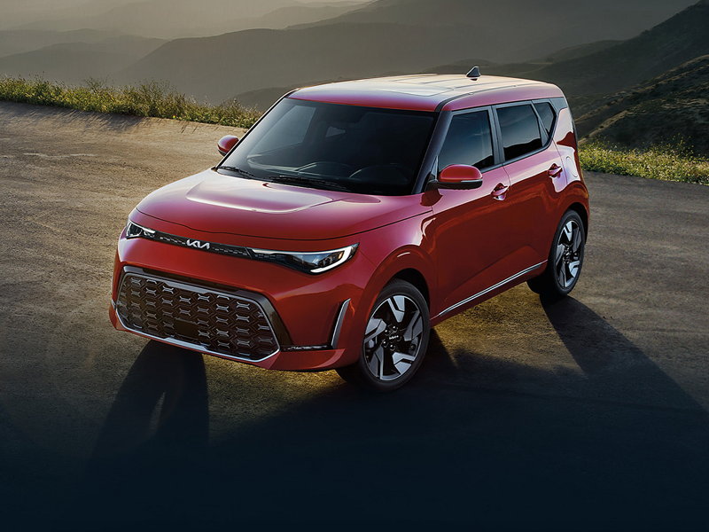 A red Kia Soul parked on a mountain road