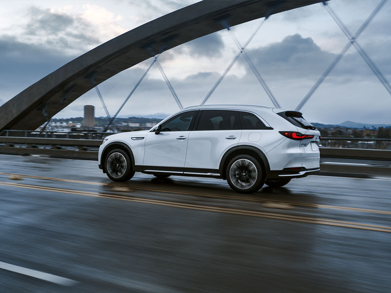 White Mazda SUV driving on a bridge in a city