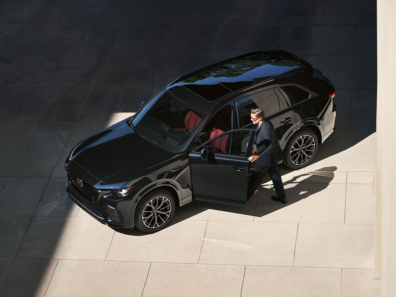 Overhead view of a man getting inside of a black Mazda SUV
